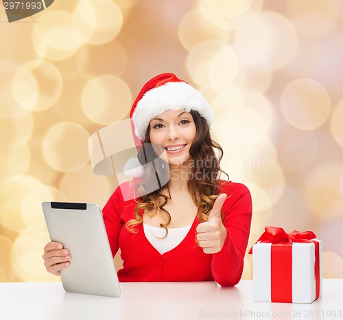 Image of smiling woman in santa hat with gift and tablet pc