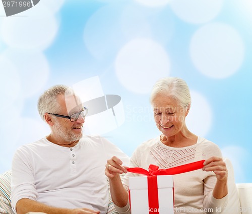 Image of happy senior couple with gift box at home