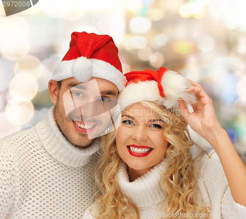 Image of smiling couple in sweaters and santa helper hats