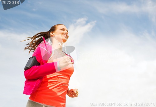Image of smiling young woman running outdoors