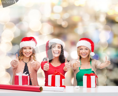 Image of smiling women in santa helper hats packing gifts