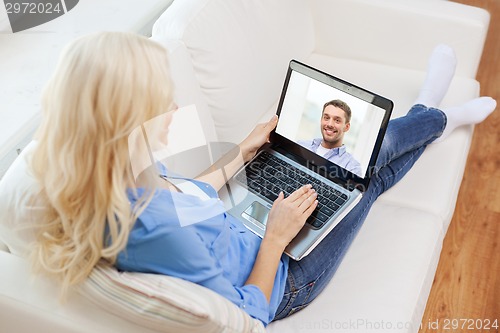 Image of smiling woman with laptop computer at home