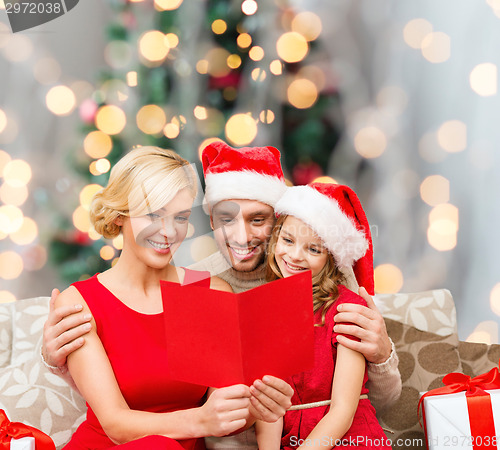 Image of happy family in santa hats with greeting card