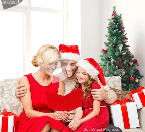 Image of happy family in santa helper hats with gift boxes