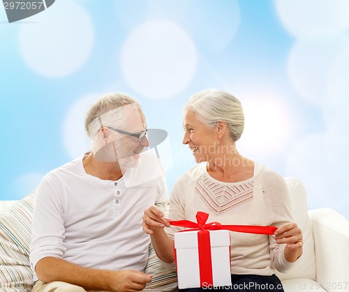 Image of happy senior couple with gift box at home