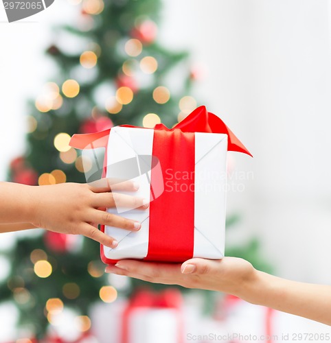 Image of close up of child and mother hands with gift box