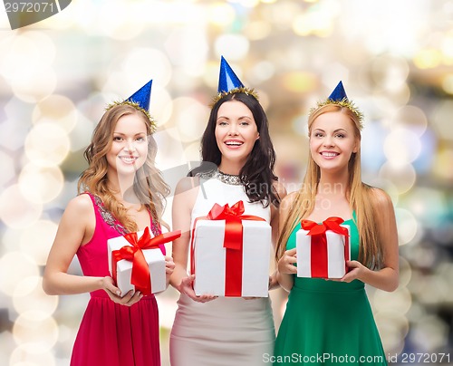 Image of smiling women in party caps with gift boxes