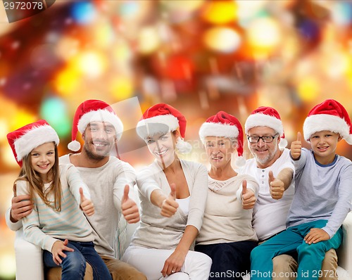 Image of happy family in santa hats showing thumbs up