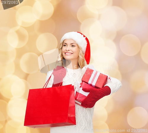 Image of smiling young woman in santa helper hat with gifts