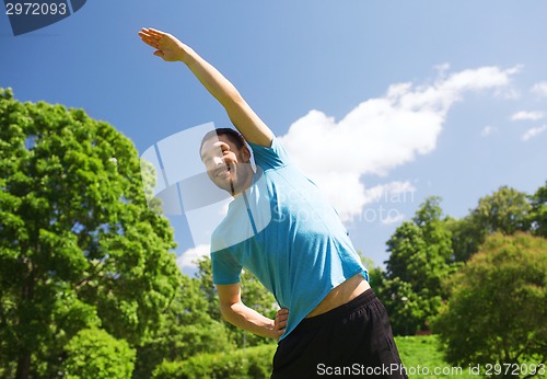 Image of smiling man stretching outdoors