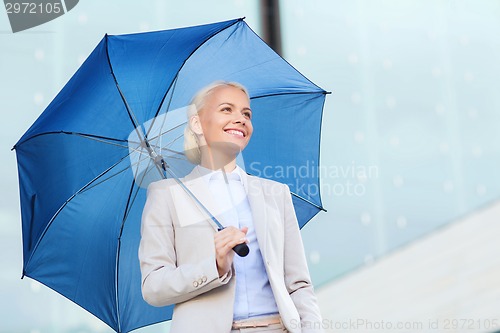 Image of young smiling businesswoman with umbrella outdoors