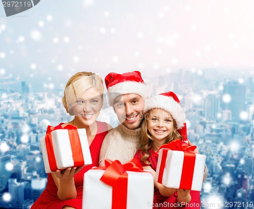 Image of happy family in santa helper hats with gift boxes