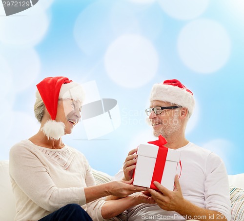 Image of happy senior couple with gift box at home