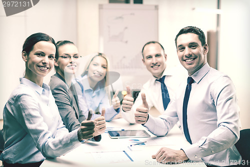 Image of business team showing thumbs up in office