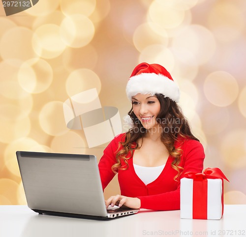 Image of smiling woman with gift box and laptop