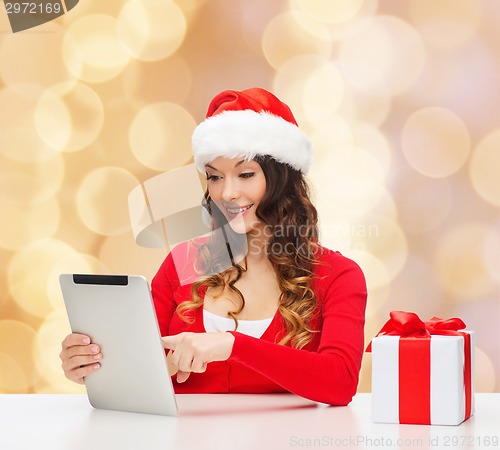 Image of smiling woman in santa hat with gift and tablet pc