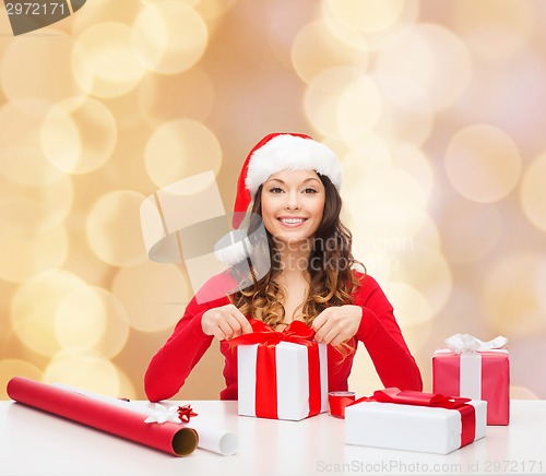 Image of smiling woman in santa helper hat packing gifts