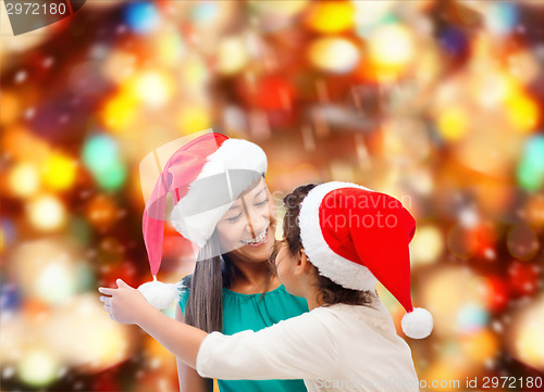 Image of happy mother and girl in santa hats