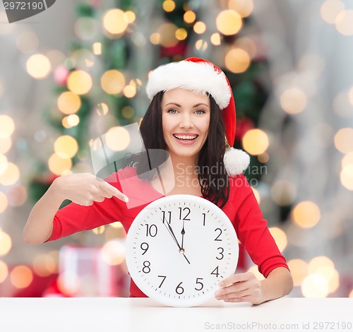 Image of smiling woman in santa helper hat with clock