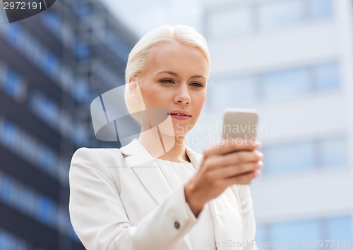 Image of serious businesswoman with smartphone outdoors