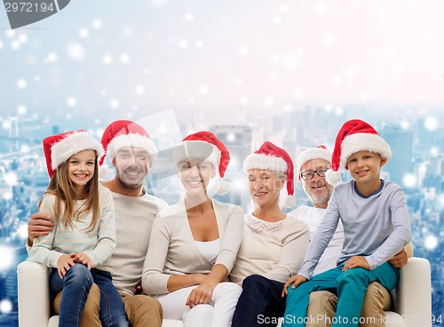 Image of happy family in santa helper hats sitting on couch