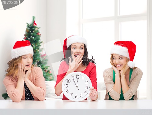 Image of smiling women in santa helper hats with clock