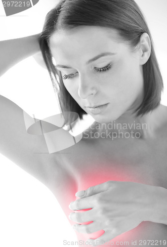 Image of woman checking breast for signs of cancer