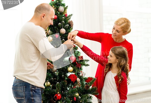 Image of smiling family decorating christmas tree at home