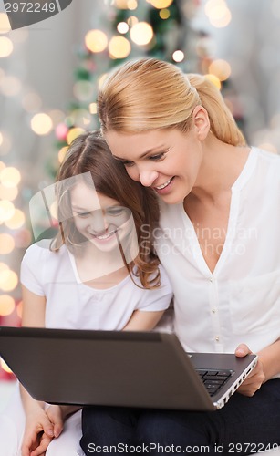 Image of smiling mother and little girl with laptop
