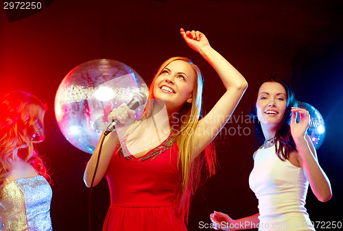 Image of three smiling women dancing and singing karaoke