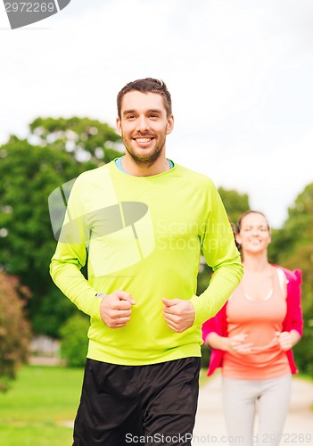 Image of smiling couple running outdoors