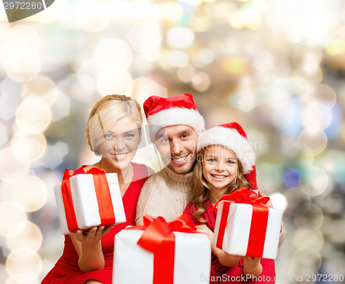 Image of happy family in santa helper hats with gift boxes
