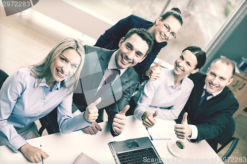 Image of business team showing thumbs up in office