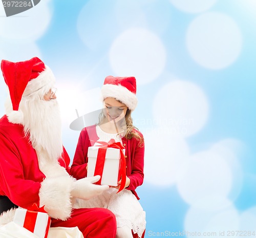 Image of smiling little girl with santa claus and gifts