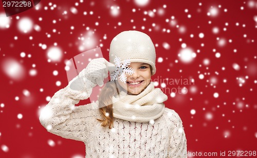 Image of smiling girl in winter clothes with big snowflake