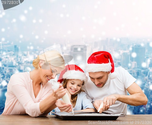 Image of happy family in santa helper hats cooking