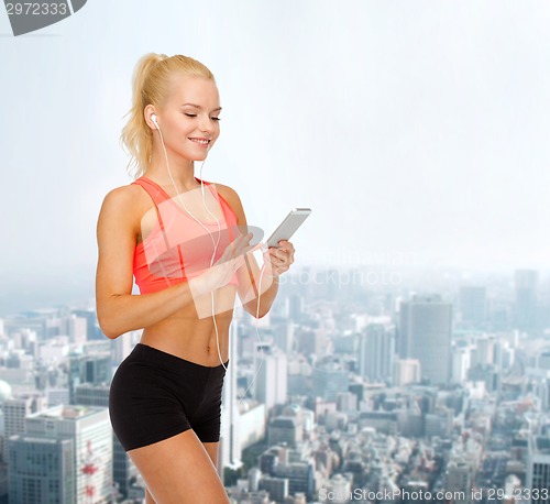 Image of smiling sporty woman with smartphone and earphones