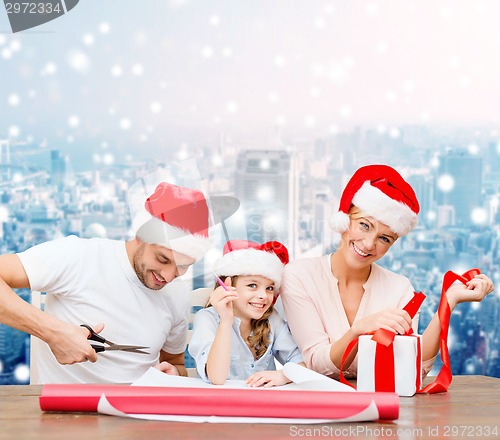 Image of happy family in santa helper hats packing gift