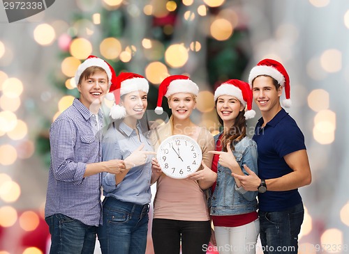 Image of group of teenagers in santa helper hats with clock