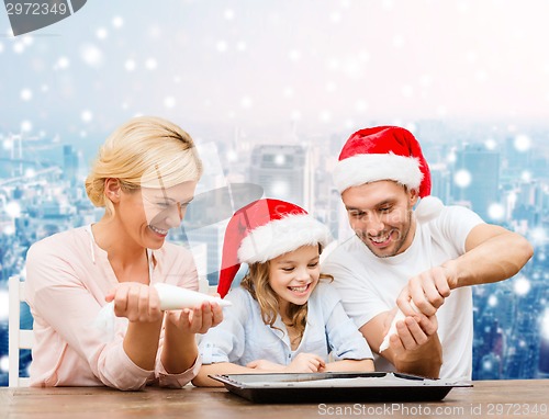 Image of happy family in santa helper hats cooking