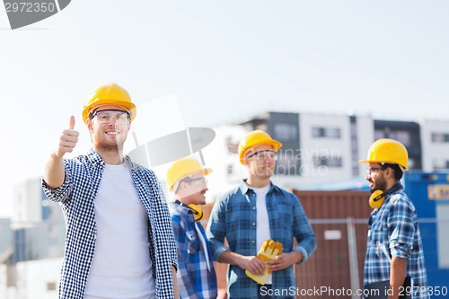 Image of group of smiling builders in hardhats outdoors