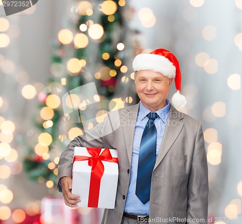 Image of smiling man in suit and santa helper hat with gift