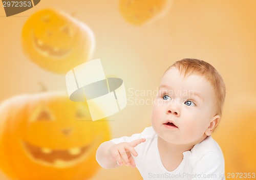 Image of smiling baby over pumpkins background