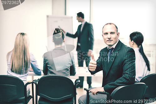 Image of businessman with team showing thumbs up in office