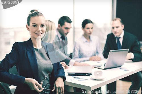 Image of businesswoman with glasses with team on the back