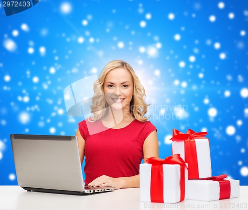 Image of smiling woman in red shirt with gifts and laptop