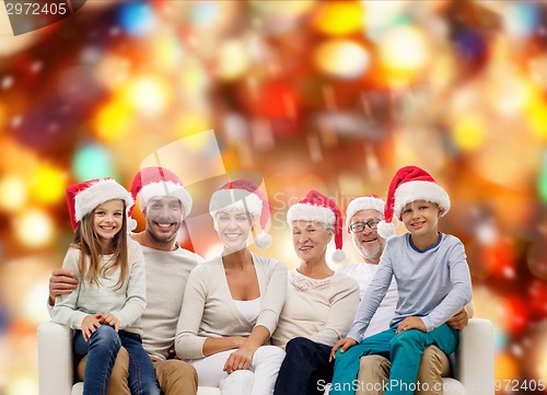 Image of happy family in santa helper hats sitting on couch