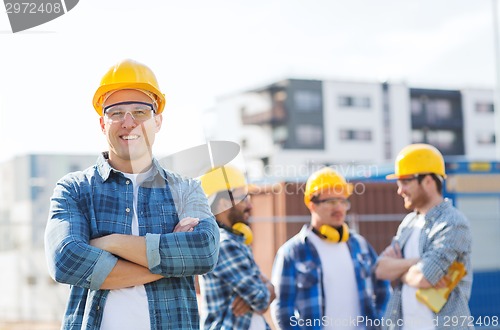 Image of group of smiling builders in hardhats outdoors