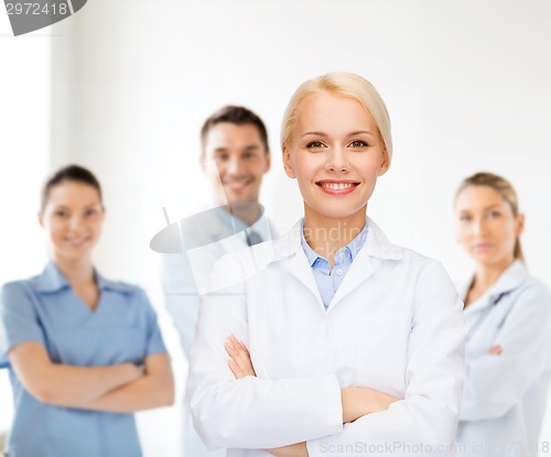 Image of smiling female doctor with group of medics