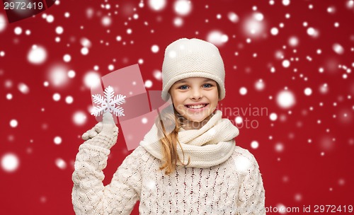 Image of smiling girl in winter clothes with big snowflake